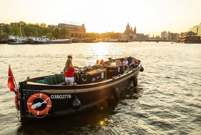 Barca aperta con skipper al tramonto sui canali di Amsterdam